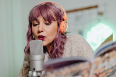 mujer con audifonos cantando frente a microfono