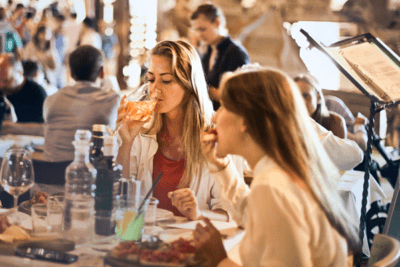 mujeres comiendo y bebiendo en restaurante de Naples