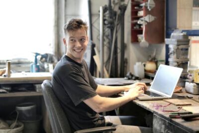 hombre sonriendo frente a laptop en su negocio