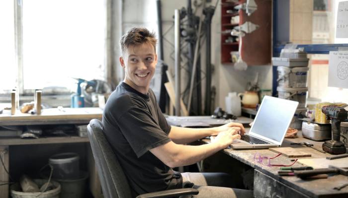 hombre sonriendo frente a laptop en su negocio