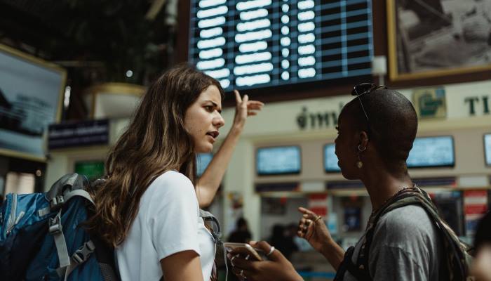 amigas mirando informacion en pantallas de un aeropuerto