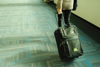 mujer caminando con maleta por pasillo de aeropuerto