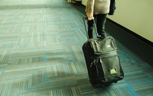 mujer caminando con maleta por pasillo de aeropuerto